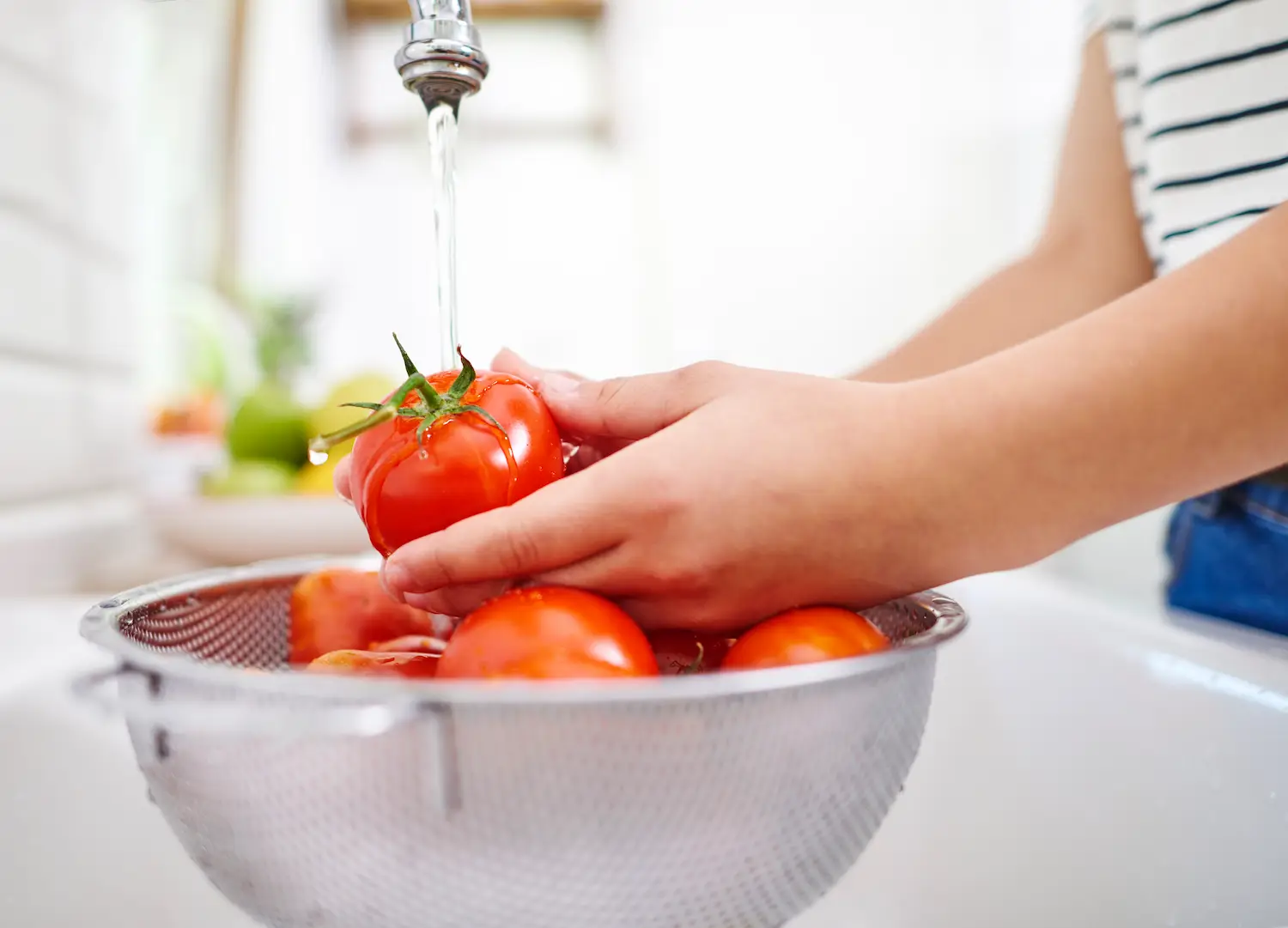 Pessoa higienizando uma cesta de tomates frescos